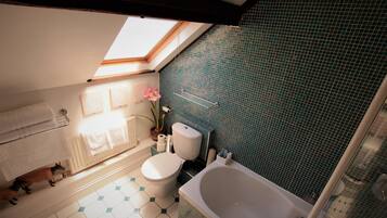 A bathroom with a skylight, a toilet, a bathtub, and a shower.