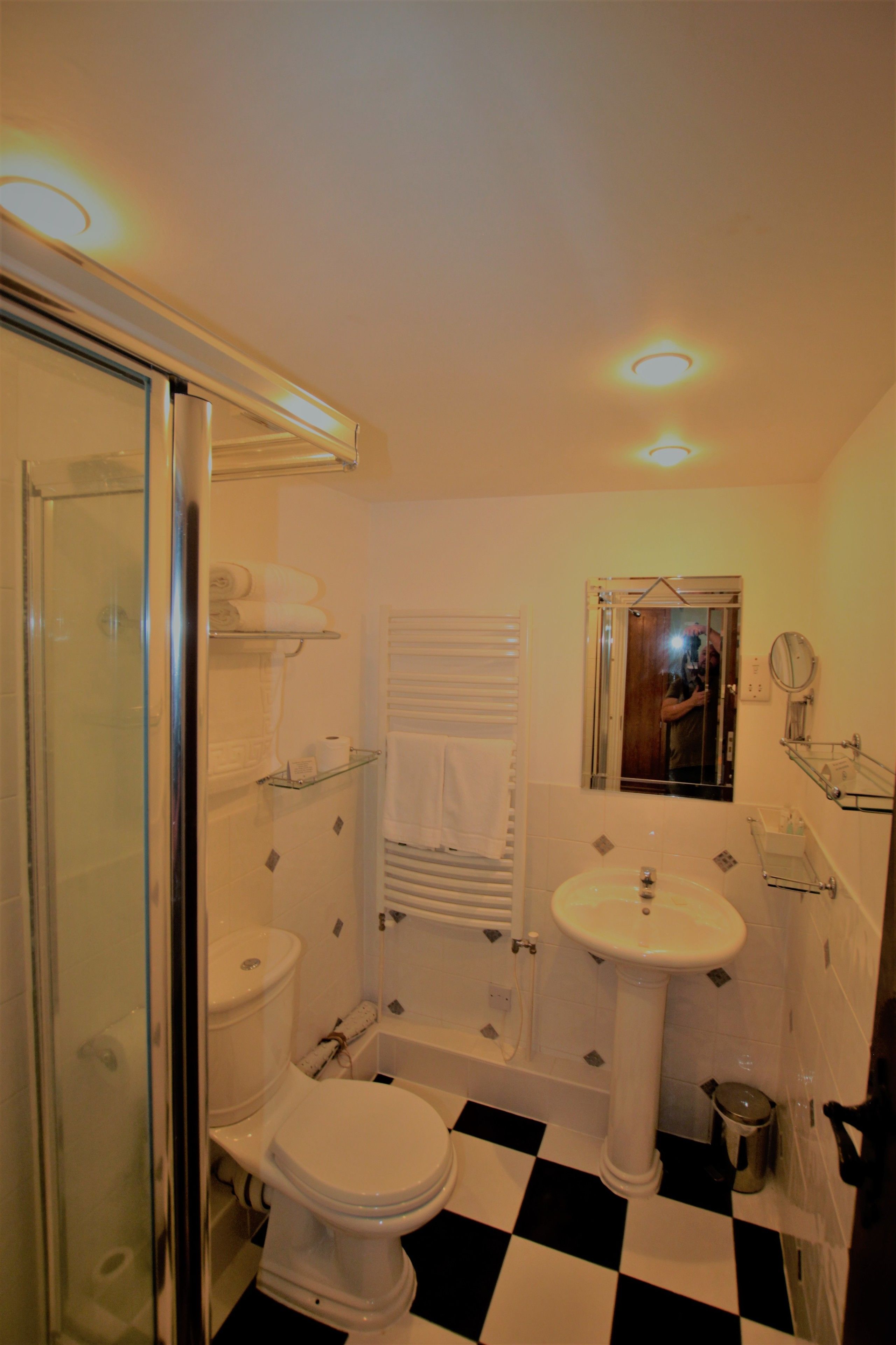 Un baño con cabina de ducha de vidrio, inodoro blanco, lavamanos y espejo.
