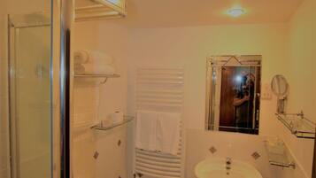 Un baño con cabina de ducha de vidrio, inodoro blanco, lavamanos y espejo.