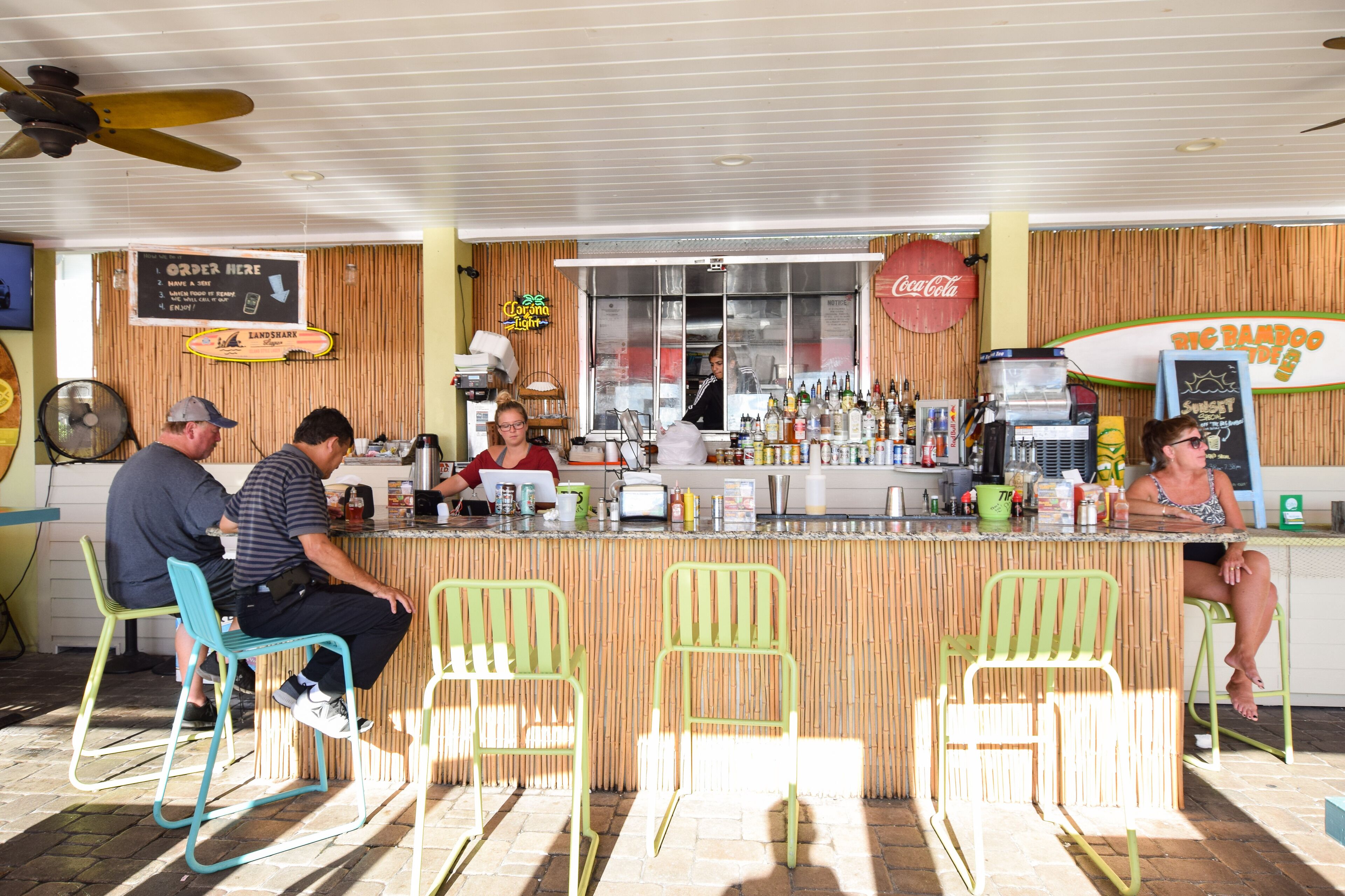 A bar with a counter, stools, and a menu board.
