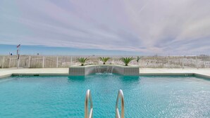 A swimming pool with a view of the beach and a fence in the background. - Beachfront Gulf Shores Condo w/ Pool (Gulf Shores)