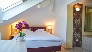 A hotel room with a bed, a nightstand, a potted orchid, a wall-mounted light, and a mirror. - Hotel Wendelstein (Wendelstein)