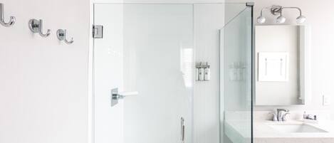 A modern bathroom with a glass-enclosed shower, a white sink, and a teal accent wall.