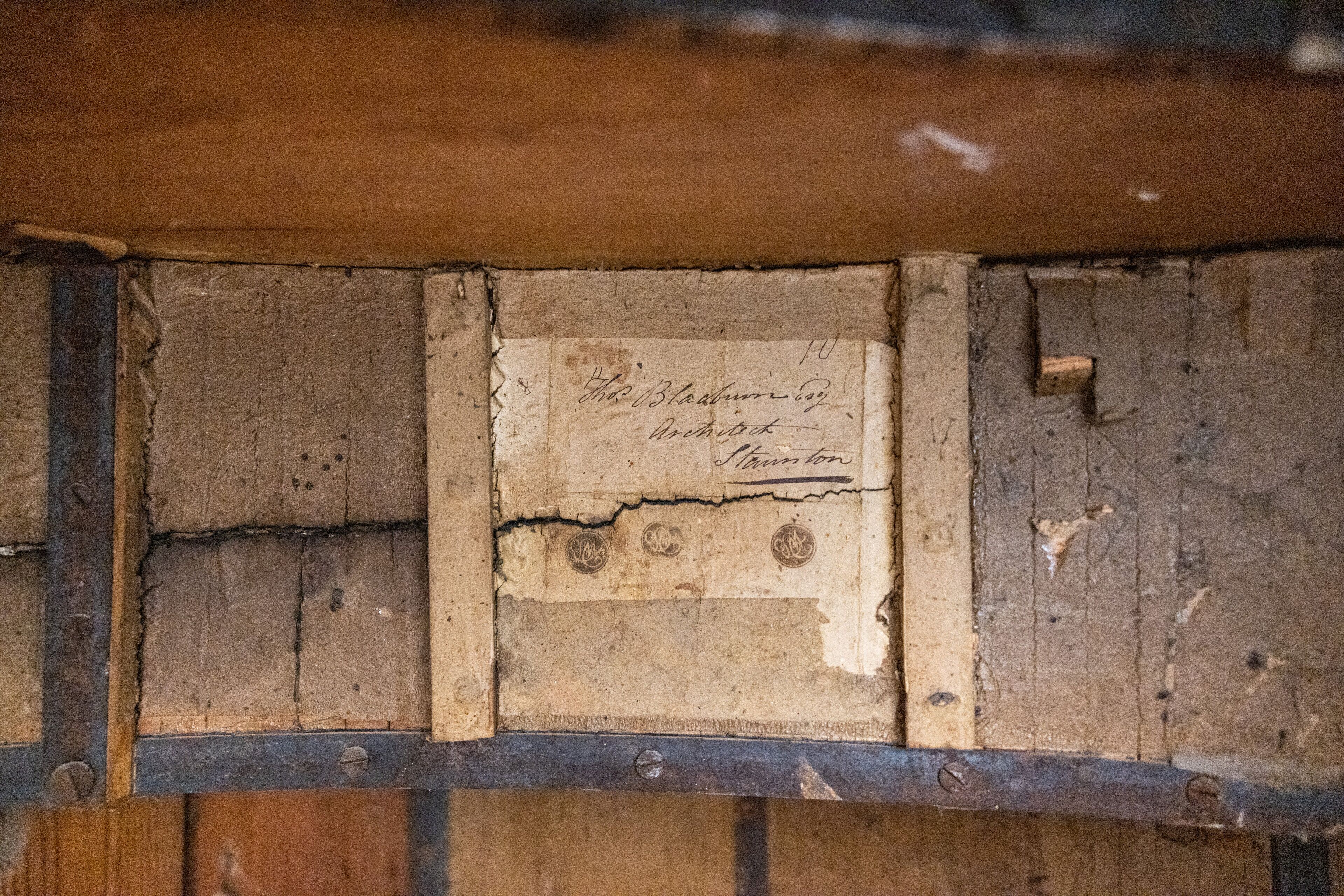 A close-up of a wooden wall with a worn, aged sign that reads "The Blacksmith's Inn" and "Arch Street, London."