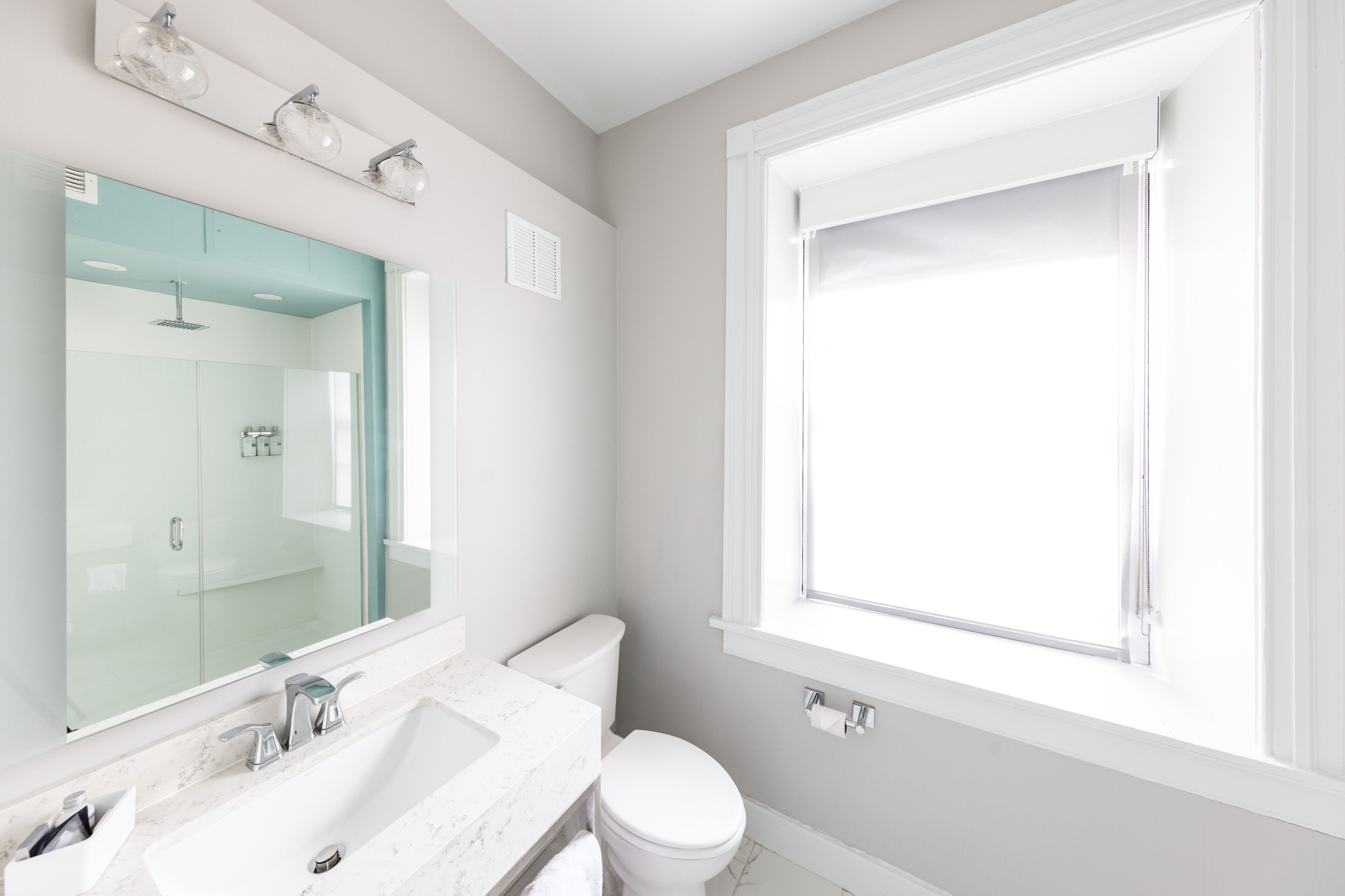 A modern bathroom with a large mirror, a sink, and a toilet.