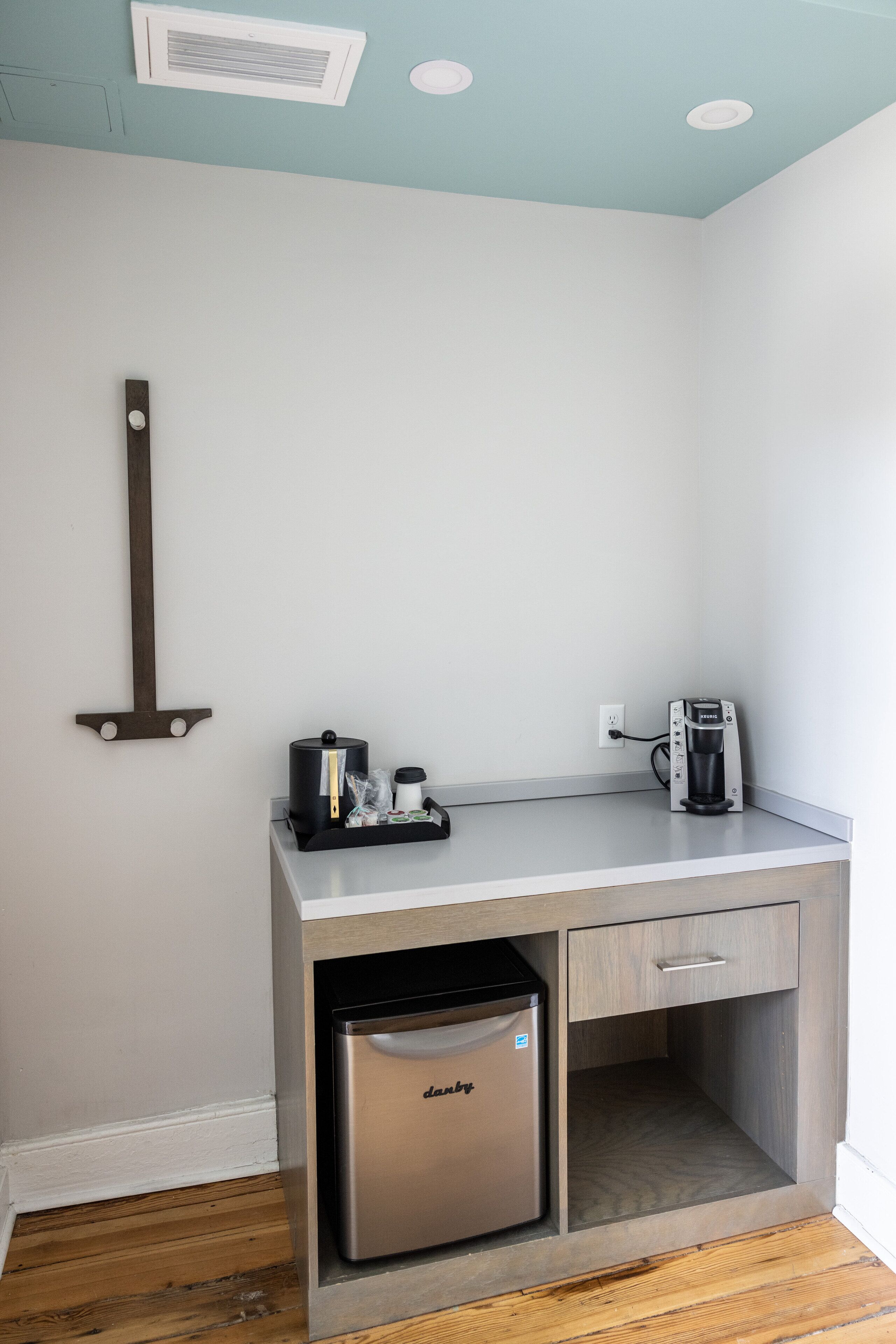 A compact kitchenette with a coffee maker, a small refrigerator, and a countertop.