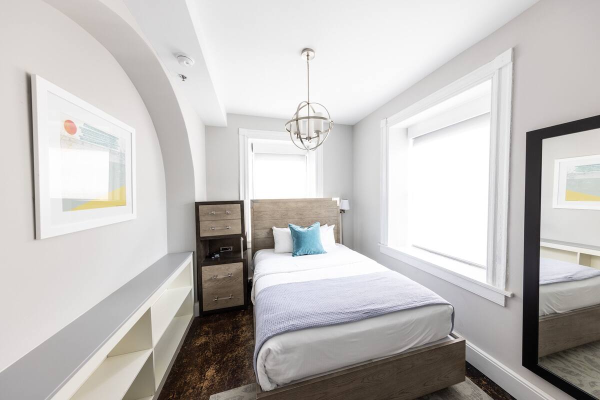 Une chambre à coucher moderne avec un grand lit, une commode, une table de chevet et un miroir.