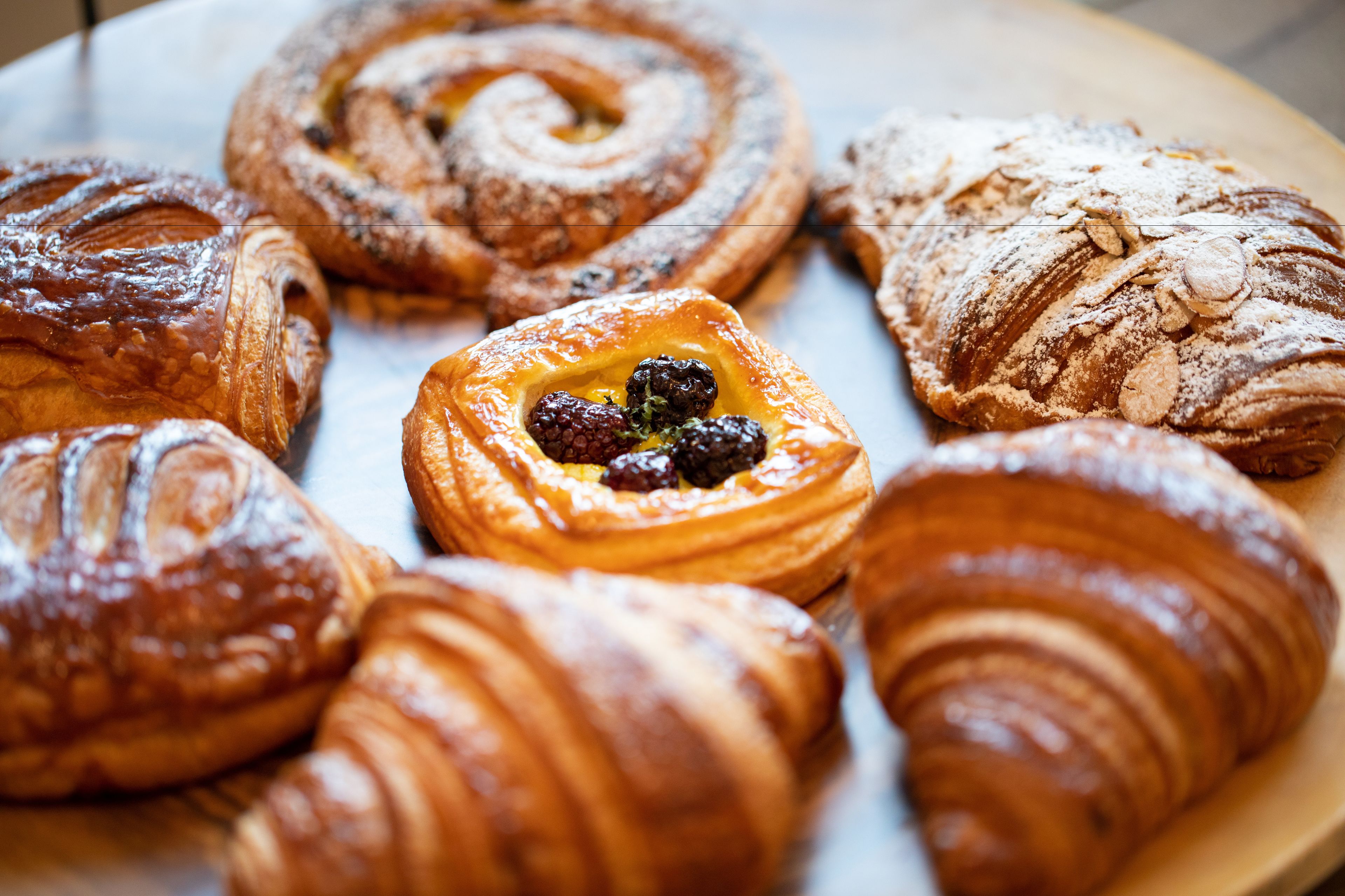 Diversas opciones de pastelería, incluyendo croissants y un pastel con relleno de frutos rojos.