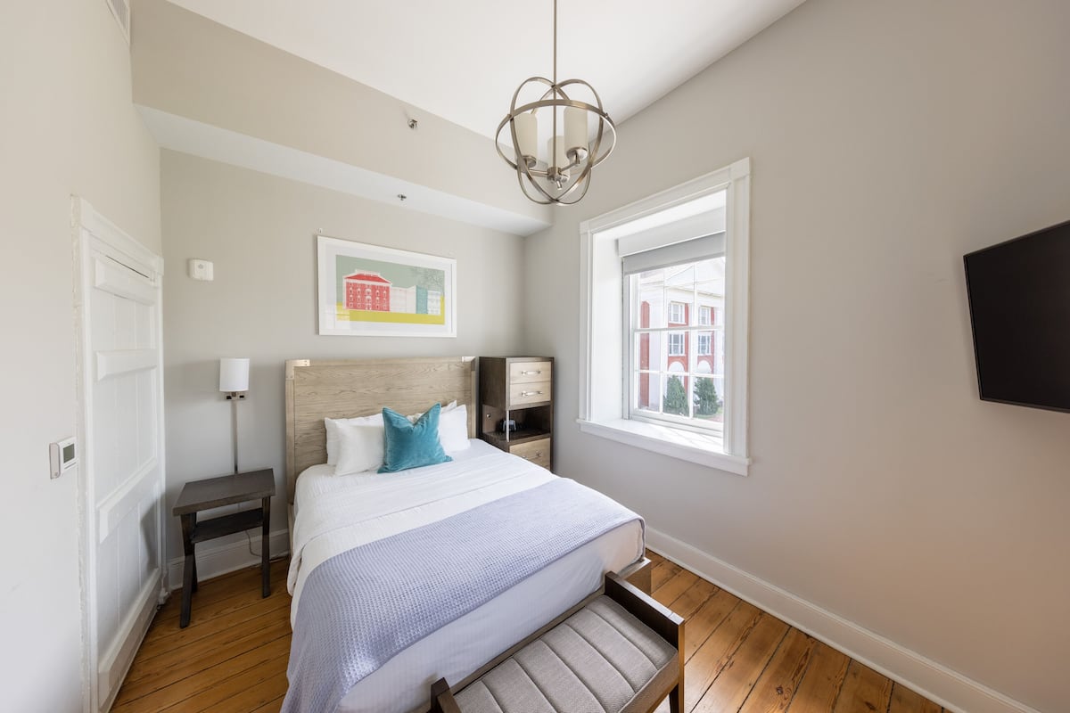 Une chambre à coucher comprenant un lit, des tables de chevet, une commode, une fenêtre avec vue et un téléviseur fixé au mur.
