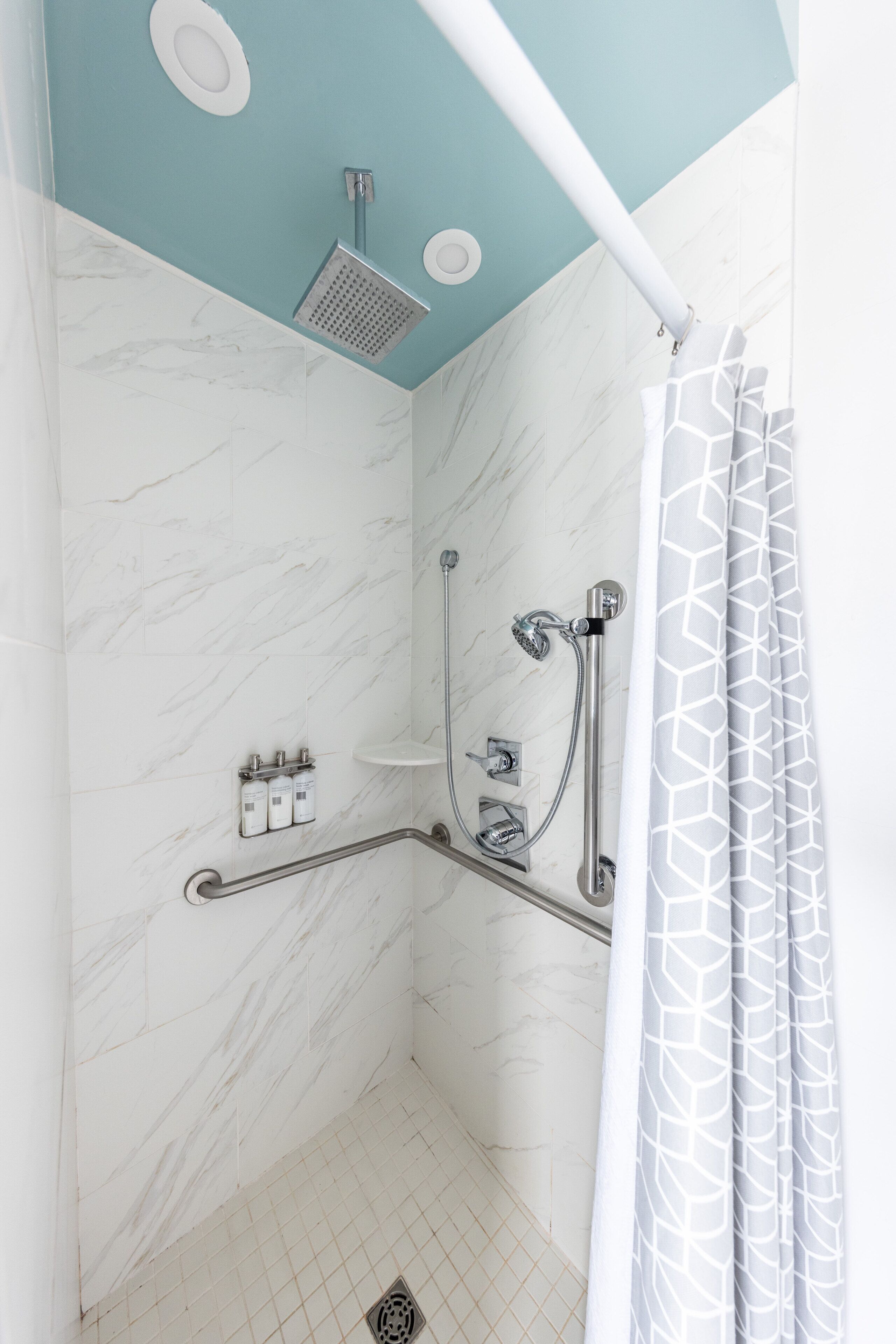 A modern shower with a handheld showerhead, a wall-mounted faucet, and a handheld showerhead.