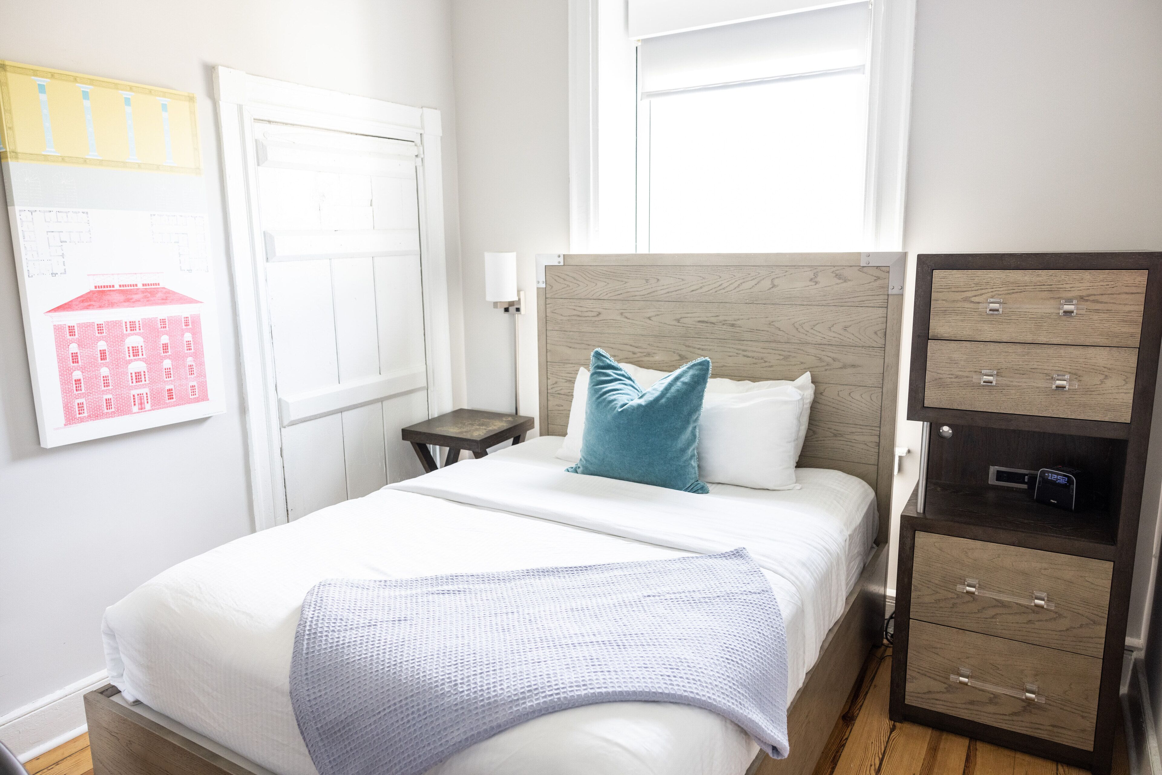 Un dormitorio ordenado con cama, mesita de noche y cómoda con cajones.