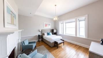 A bedroom with a bed, bedside table, lamp, and a view of the outside through large windows.
