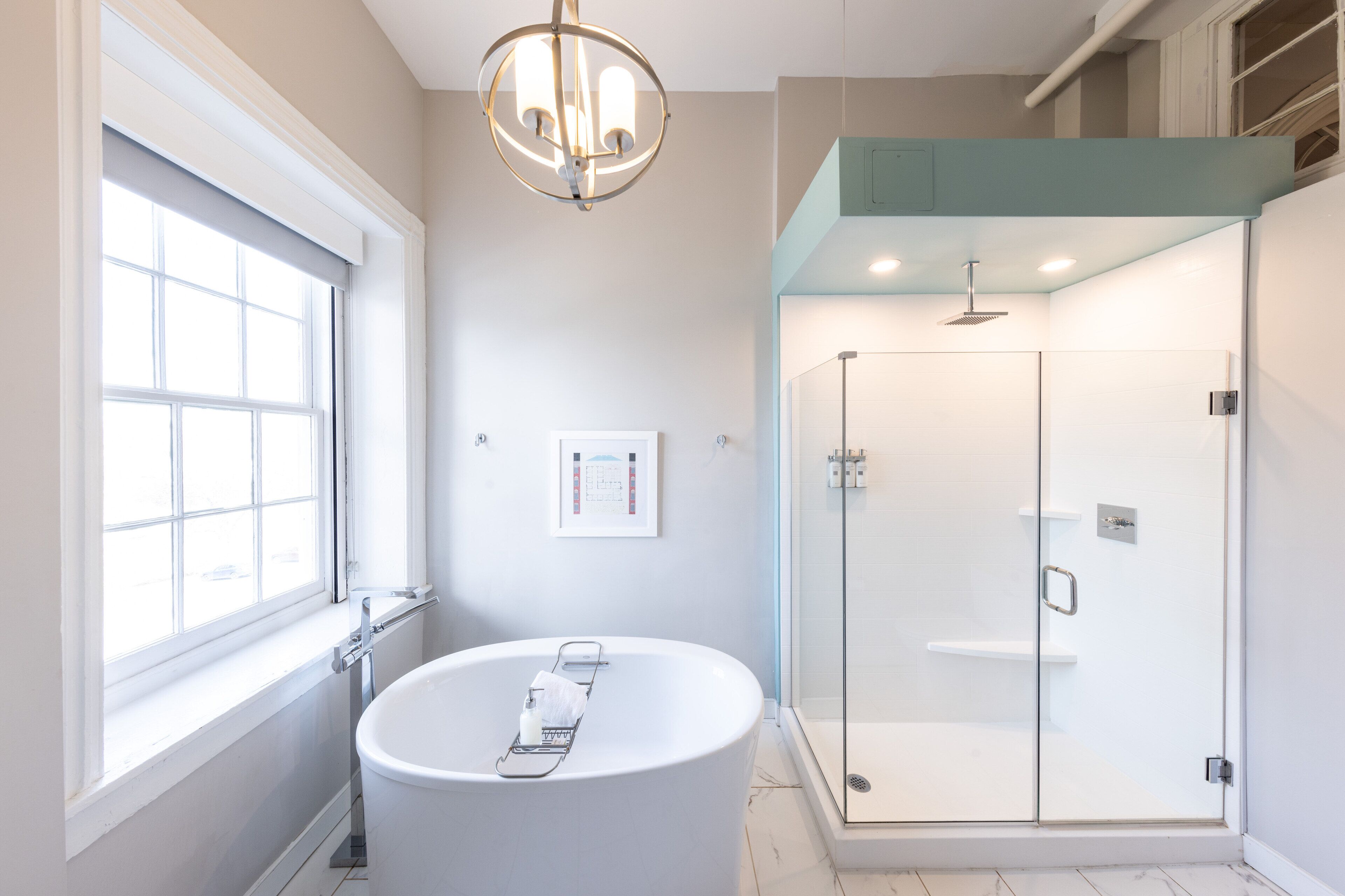 A modern bathroom with a freestanding bathtub, a glass-enclosed shower, and a window providing natural light.