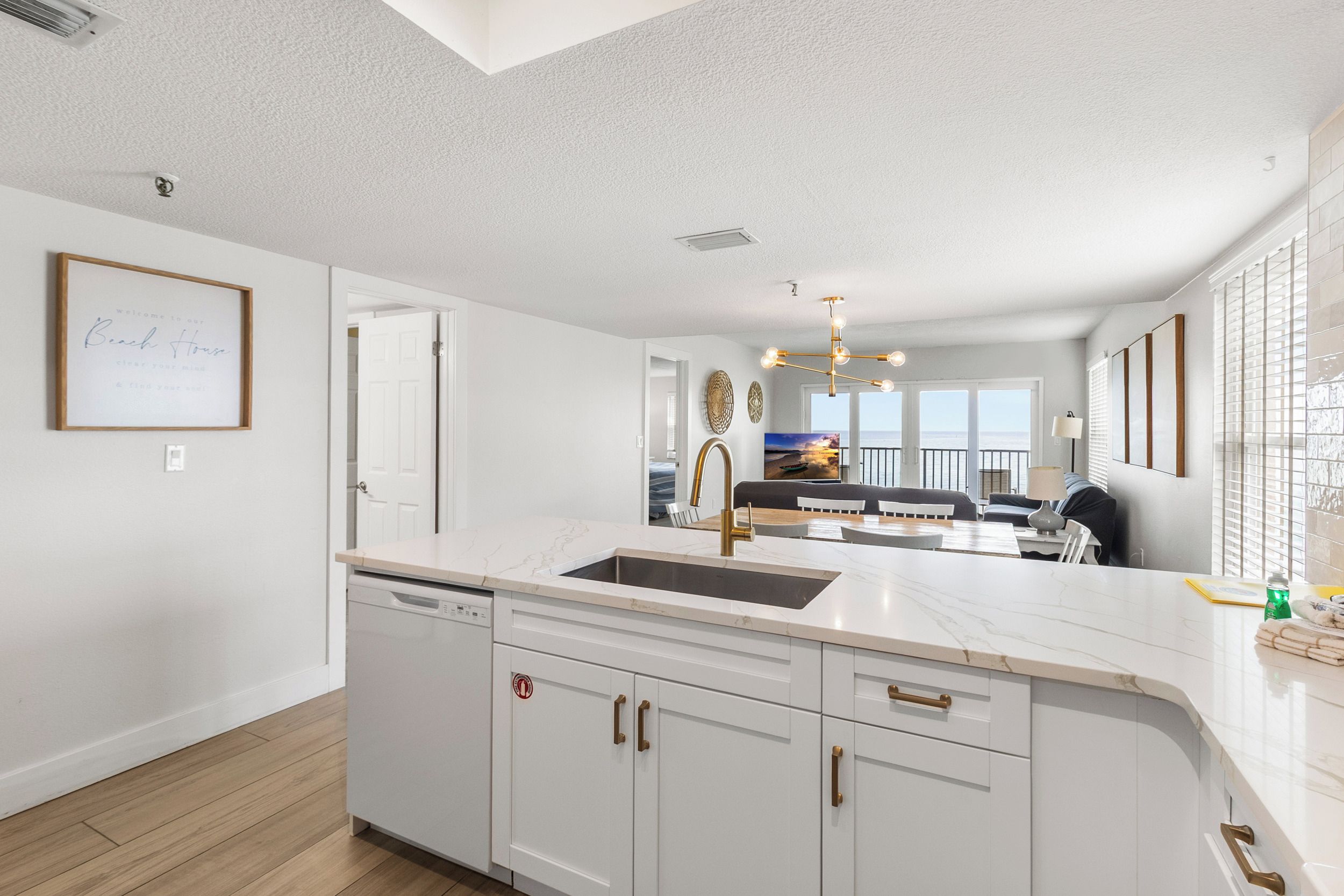 Una cocina moderna con una isla central, armarios blancos y vistas al área de estar.