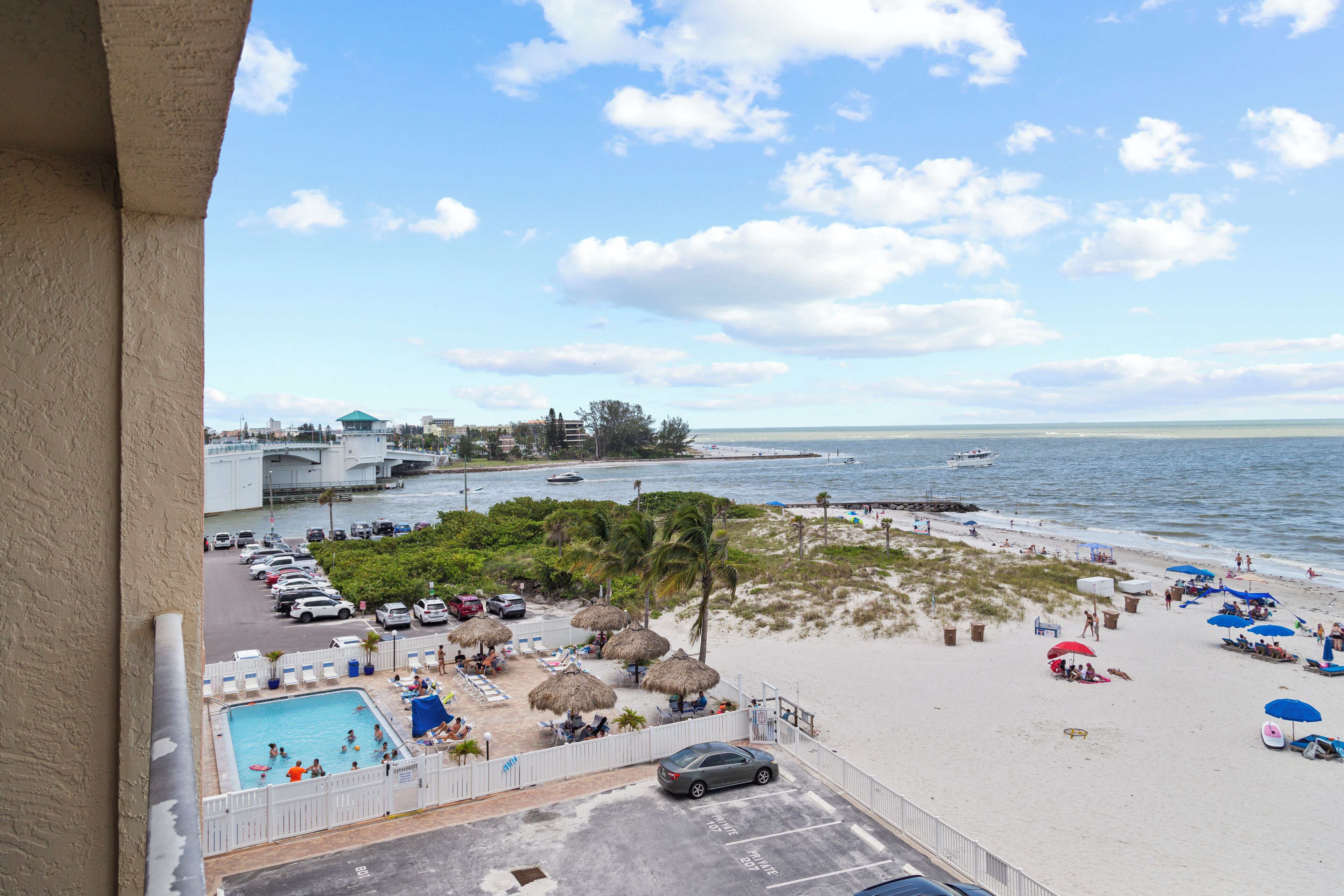 Vista para a praia com piscina, guarda-sóis e espreguiçadeiras.