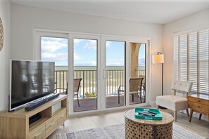 Relax on the balcony with ocean views, featuring a flat-screen TV and comfortable seating.