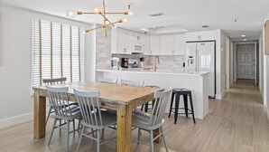 Una cocina moderna con armarios blancos, una mesa de comedor de madera y una isla central.