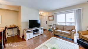 Ein Wohnzimmer mit Flachbildfernseher, einem beigen Sofa und einem Couchtisch.