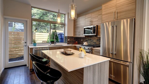 A modern kitchen with a large island, stainless steel appliances, and a view of the backyard through a sliding door. - Rooftop Views of the Space Needle & City (Seattle)