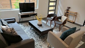 A modern living room with a sofa, chairs, a coffee table, and a TV. - Rooftop Views of the Space Needle & City (Seattle)