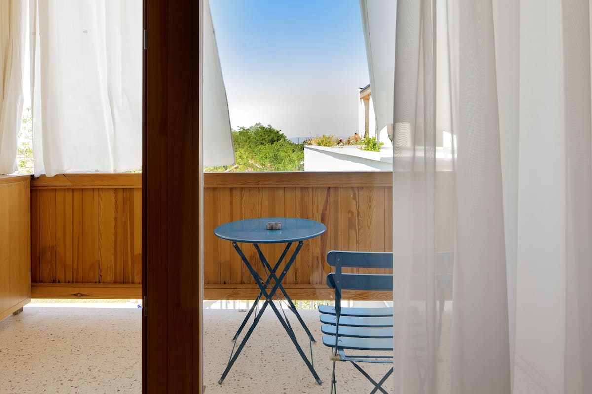 A balcony with a wooden floor, a blue table, and a blue chair.