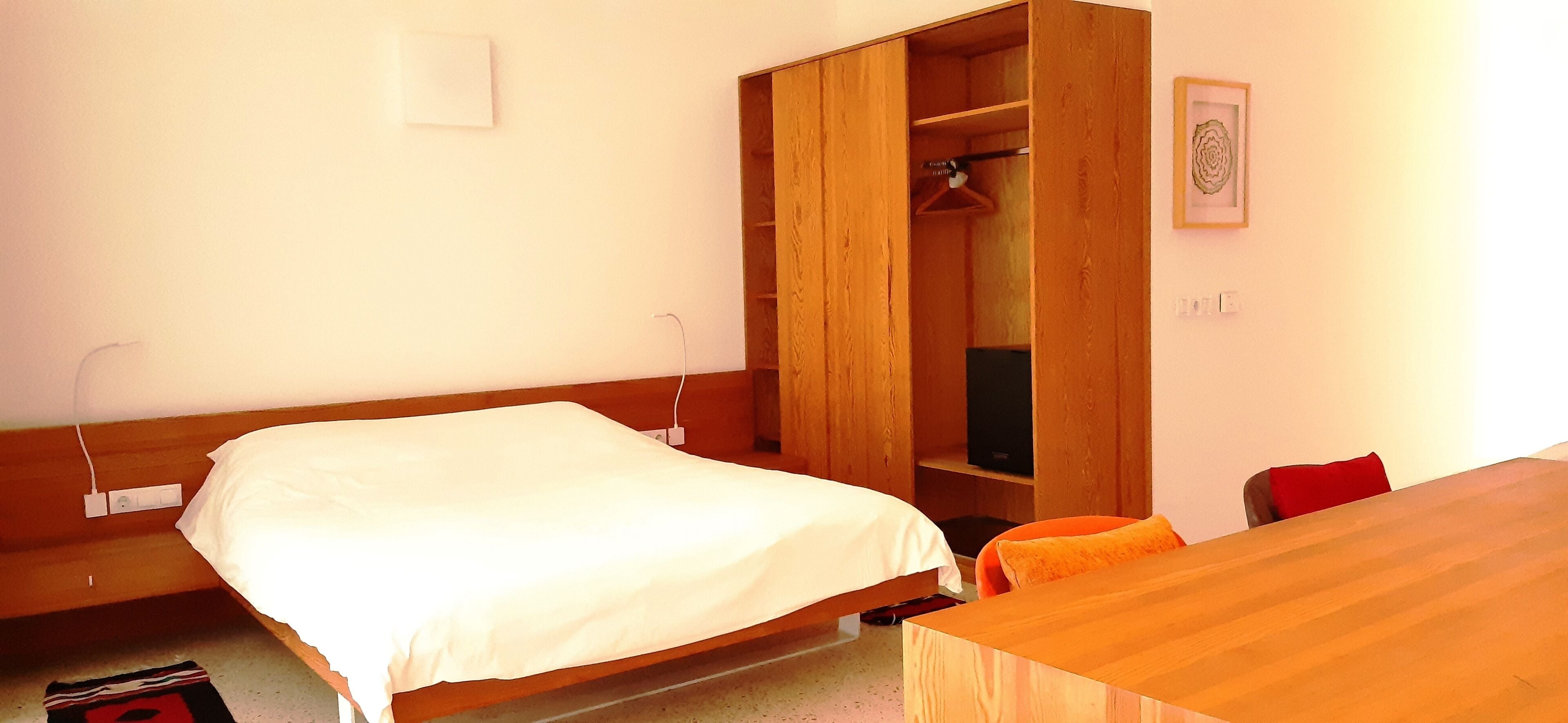 A bedroom with a wooden bed, a wardrobe, and a desk.