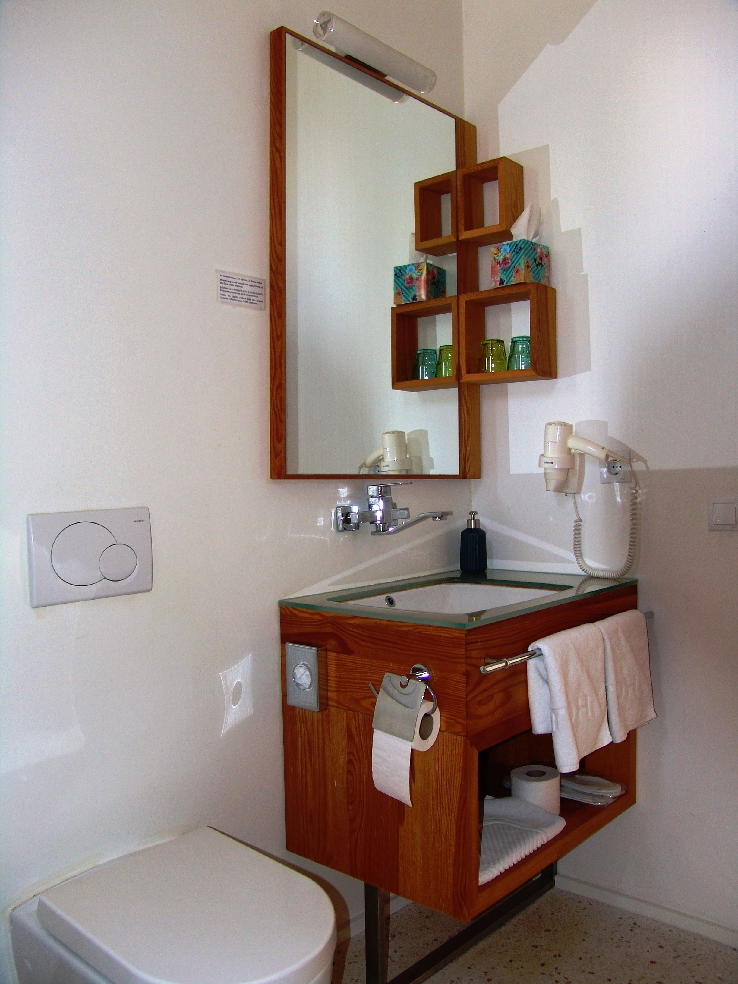 A bathroom with a wooden vanity, a mirror, a sink, a toilet, and a telephone.