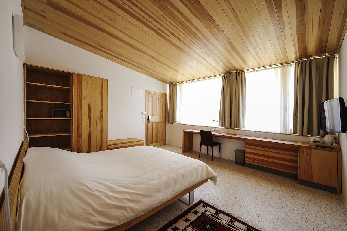 A bedroom with a bed, a desk, a chair, and a wardrobe.