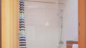 A bathroom with a shower, toilet, and wooden vanity.