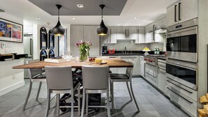 Una cocina moderna con una isla central, electrodomésticos de acero inoxidable e iluminación colgante.