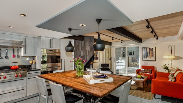 Una cocina moderna con electrodomésticos de acero inoxidable, una mesa de comedor de madera y un sofá rojo en la sala de estar.