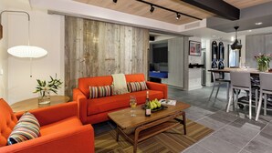 Una sala de estar moderna con techo de madera, un sofá rojo, una mesa de centro de madera y un comedor con una mesa y sillas blancas.