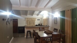 Un comedor con una mesa y sillas de madera, una cocina al fondo y un cartel que dice "NO COFFEE NO WORK".