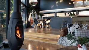 A modern kitchen with a large stove, wooden flooring, and a dining area with chairs and a table.