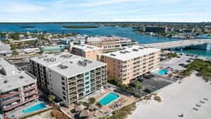 Un hotel frente a la playa con varias construcciones, piscina y zona de playa.