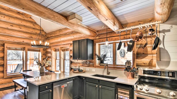 A log cabin kitchen with a central island, stainless steel appliances, and wooden beams. - Remodeled Fairplay Log Cabin w/ Wood-Burning Sauna (Fairplay)