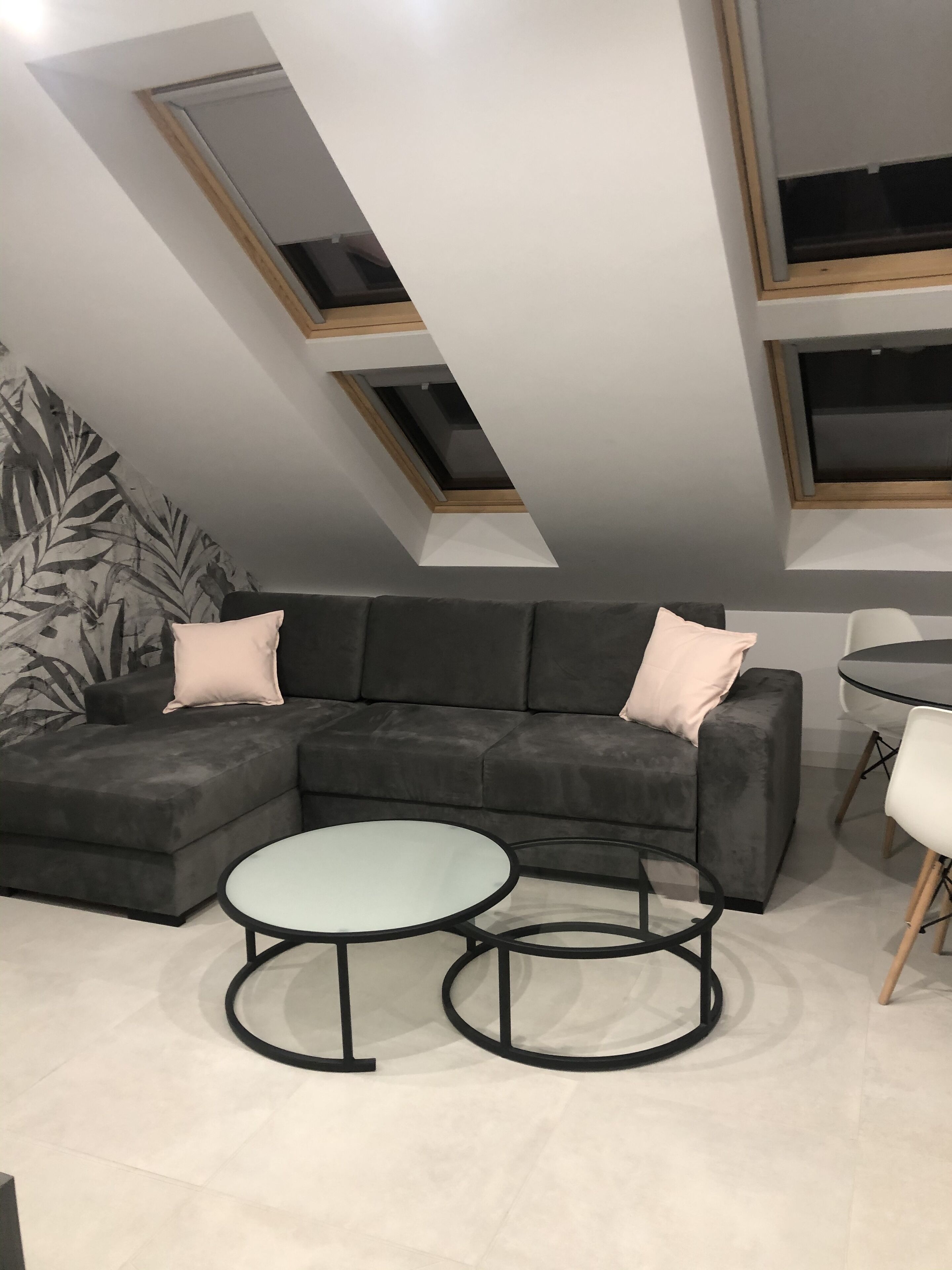 A modern living room with a sectional sofa, two round tables, and a skylight.