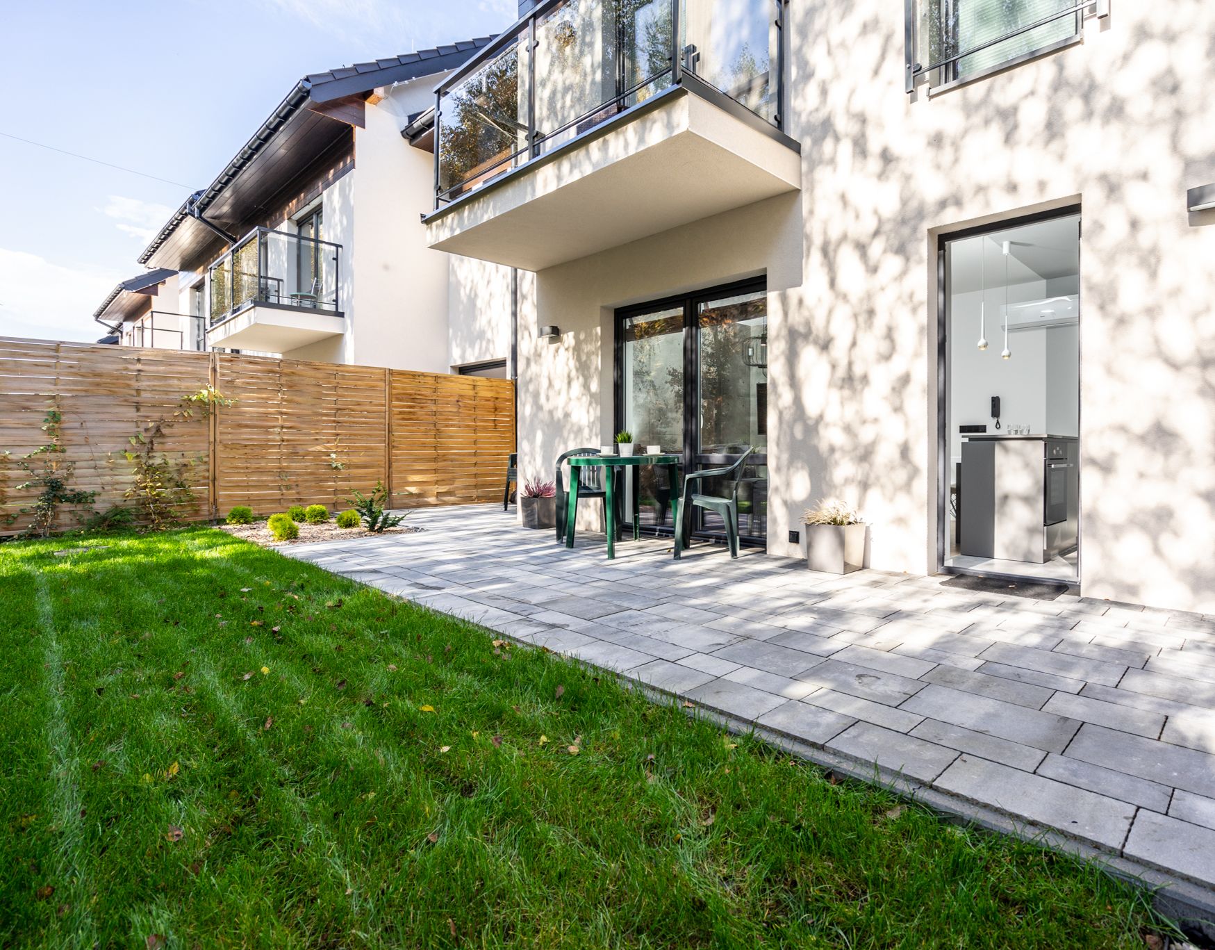 Ein modernes Haus mit Terrasse, Holzzaun und kleinem Garten.