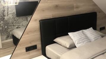 Une chambre moderne avec un lit, une table de chevet et un grand miroir qui reflète la pièce.