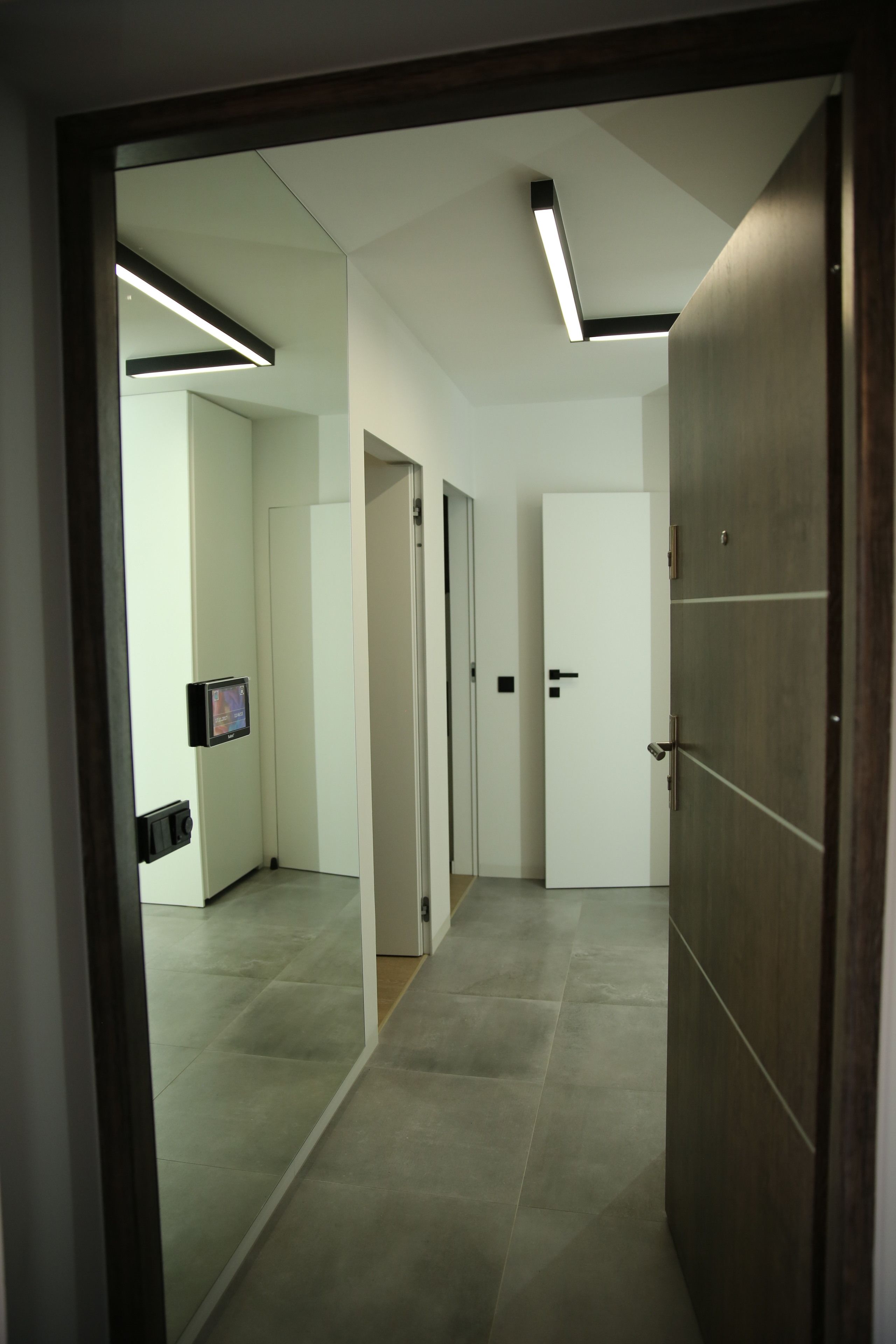 Un pasillo moderno con una puerta de madera, una puerta blanca y una puerta con manija.