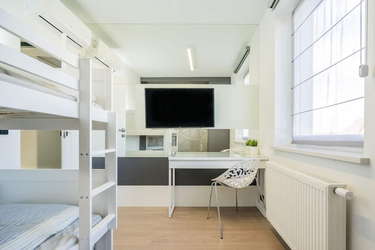 A compact room with bunk beds, a desk, a chair, a TV, and a window.