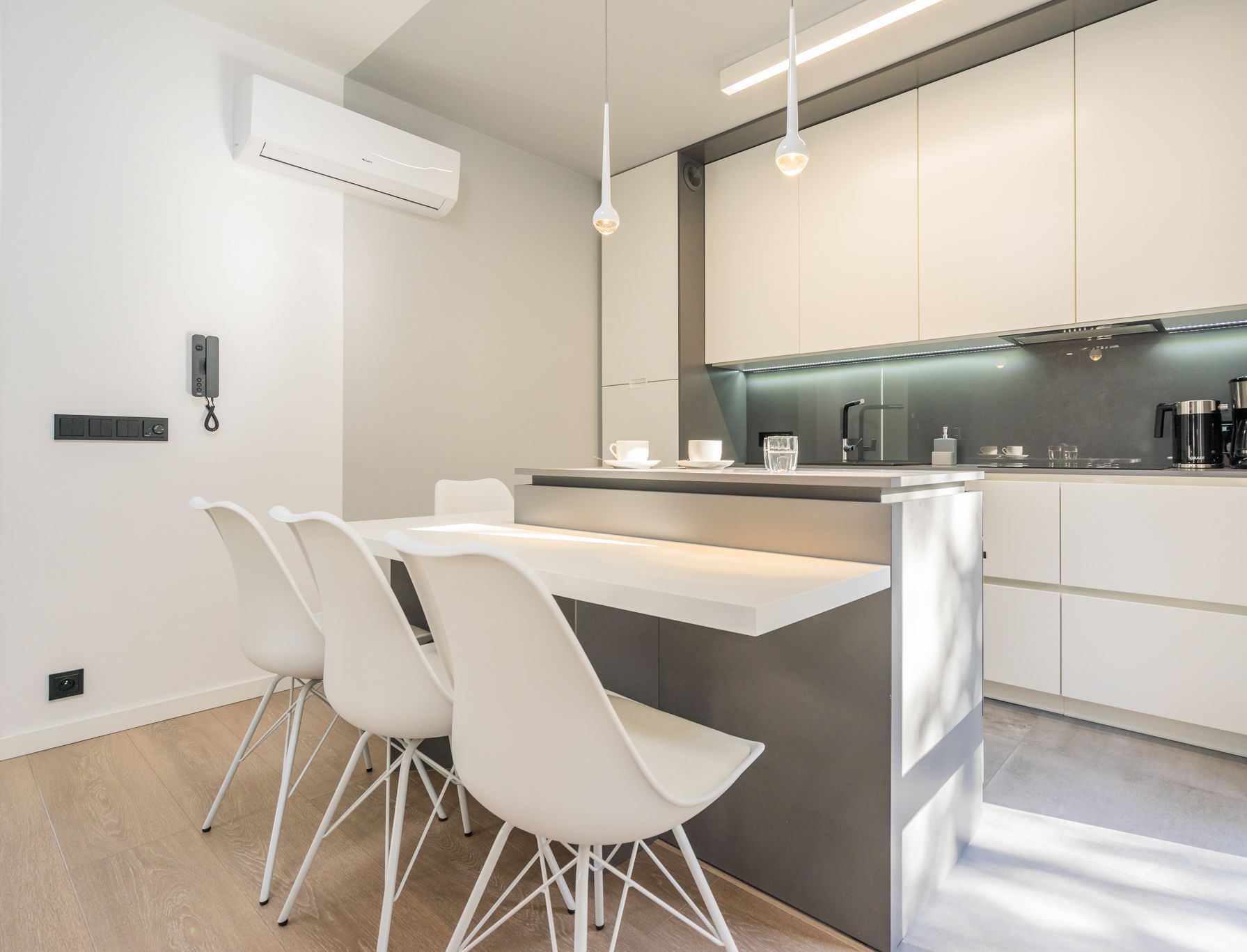 A modern kitchen with white cabinetry, a central island with seating, and a built-in oven.