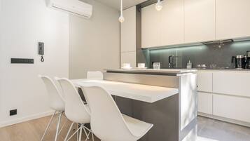 A modern kitchen with white cabinetry, a central island with seating, and a built-in oven.