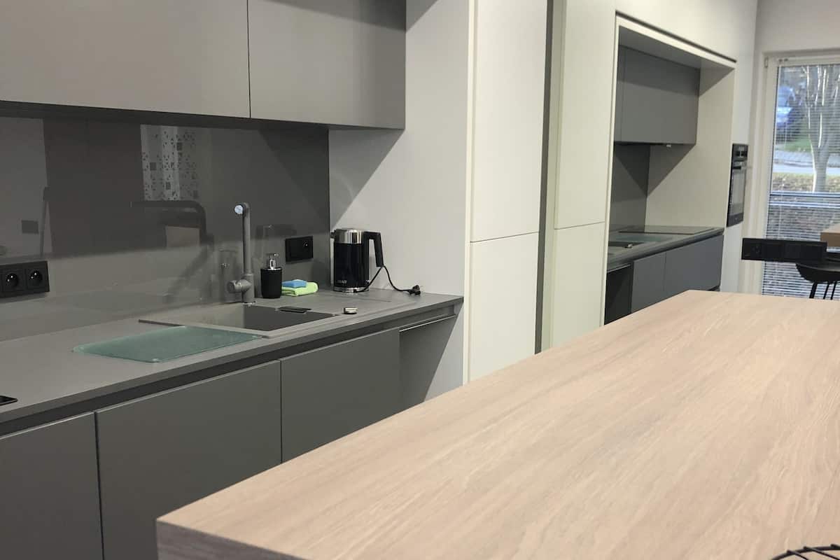 A modern kitchen with grey cabinets, a wooden dining table, and a black chair.