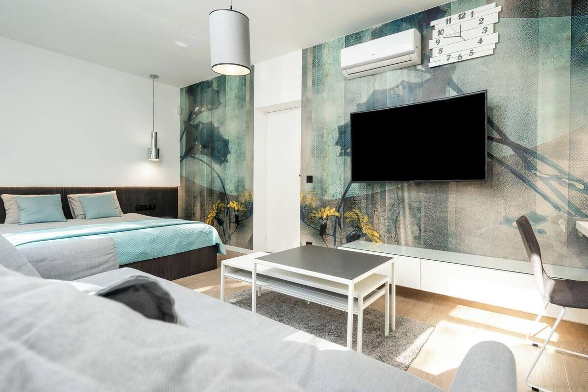 A modern bedroom with a bed, a TV, and a wall-mounted air conditioner.