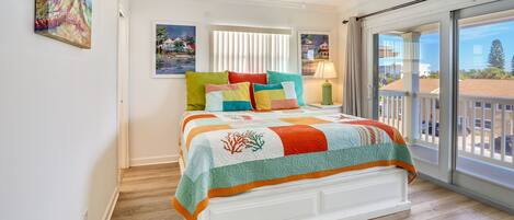 A bedroom with a bed, a ceiling fan, a window with blinds, and a view of the outside.