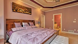Un dormitorio con una cama grande, cabecera de madera, una araña y un cuadro en la pared.