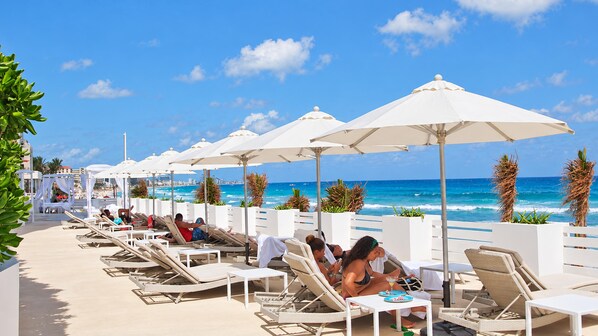 A beachside lounge area with sun loungers and umbrellas, overlooking the ocean.