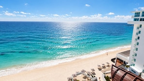 A beachfront hotel with a pool area and a view of the ocean.