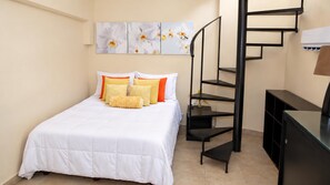 A bedroom with a bed, pillows, a wall-mounted artwork, a black metal staircase, and a dresser.